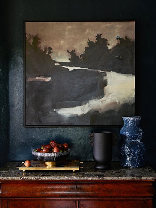 Forget the admonishment not to mix black and blue. Here the predominantly black artwork and the black vase make the deep blue wall seem lighter in comparison. Find the tray here. Photo by Frank Francis.
